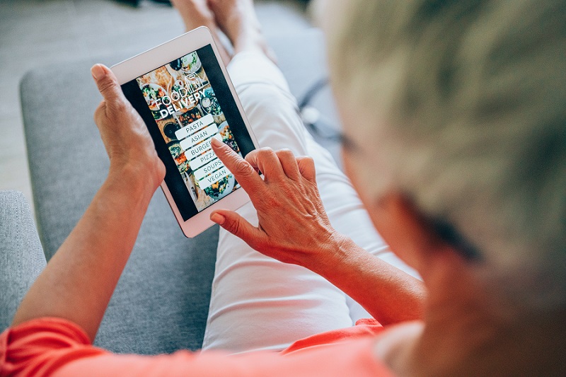 Woman ordering food online on a electronic device at home.
